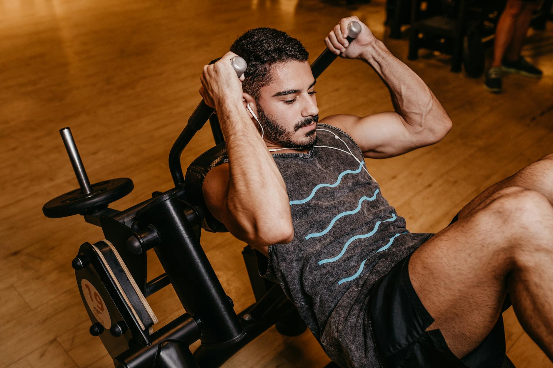 Man in Black and White Tank Top Sitting on Black Exercise Equipment