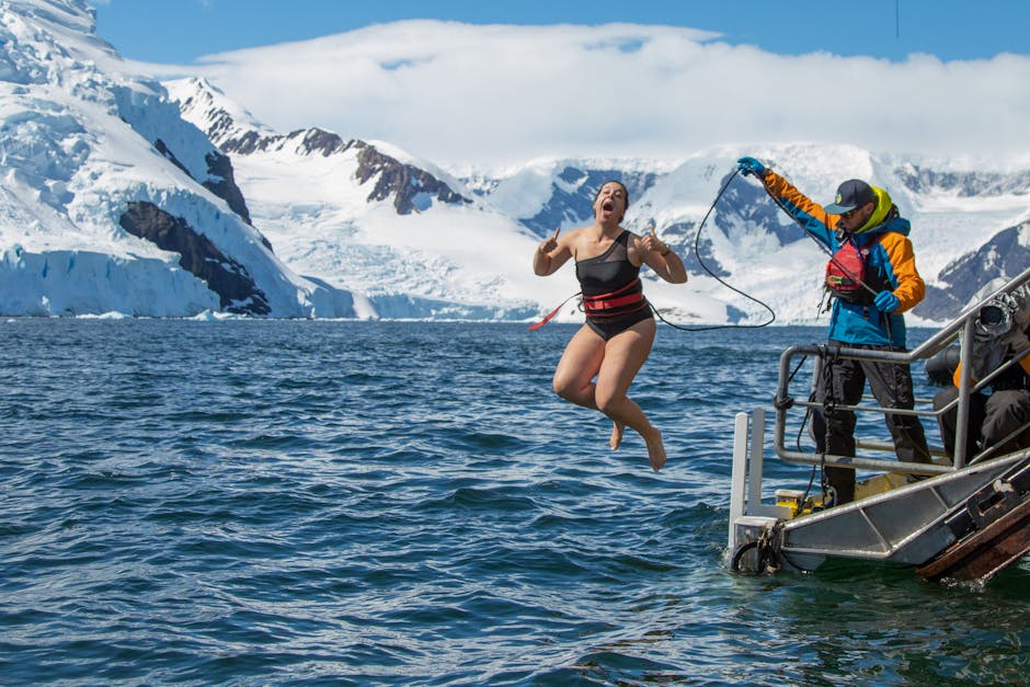 Woman plunging into icy Antarctic waters, embracing adventure and excitement.